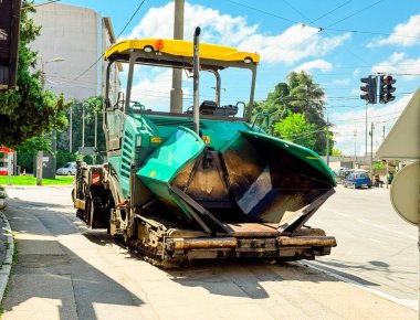 Şehir caddesindeki asfalt kaldırım makinesinin önü. Kentsel altyapı, karayolu inşaatı ve ağır endüstriyel mühendislik ekipmanları faaliyet gösteriyor