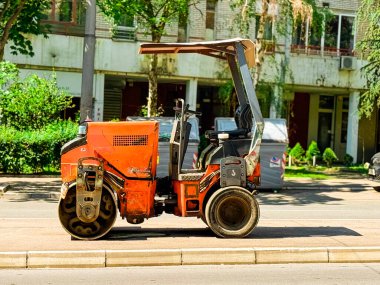 Orange Road Roller konut binalarının yakınındaki caddeye park etmiş. Asfalt sıkıştırma, kentsel altyapı ve belediye yol çalışması projelerinde kullanılan endüstriyel makine