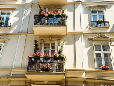 Çiçekler ve bitkilerle süslenmiş balkonları olan apartman cephesi. Mimari ayrıntı yaşam tarzı, şehir yeşilliği ve Avrupa mirasını sembolize ediyor