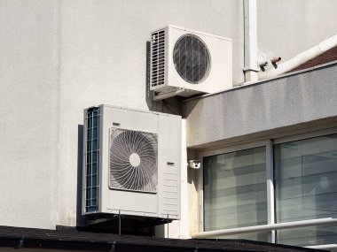 Pencerenin ve balkonun yanındaki dış bina duvarına klima takılmış. Şehir mimarisi, havalandırma teknolojisi ve modern ev altyapısı..