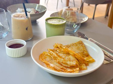 Sosu olan ince krepler. Buzlu kahve ve matcha latte ile kahvaltı.