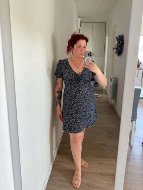 Çiçekli bir yaz elbisesi içinde aynalı selfie çeken bir kadın. Günlük çevrede moda, kadınlık ve günlük yaşam tarzı