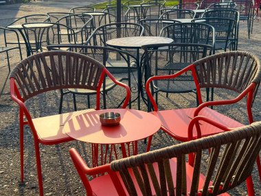 Kırmızı plastik sandalyeler ve açık kafe terasında kareli bir masa. Sokak yemekleri, günlük atmosfer ve günlük yaşam tarzı.