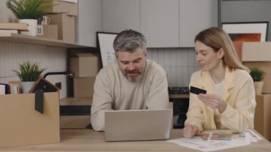 Aile, yeni evdeki bir kart ve dizüstü bilgisayarla yeni bir daireden yeni bir daire satın almak için para ödüyor. Yeni ev ve teknoloji kavramı