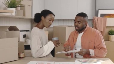 Afrikalı Amerikalı çift gelecek için tasarımı seçiyor ve renkler hakkında konuşuyorlar. Mutlu çift ev tasarımından bahsediyor. Yeni ev ve taşınma konsepti
