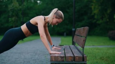 Beyaz atlet kadın yedek kulübesinde antrenman yapıyor, kulaklık takıyor, egzersiz yaparken müzik dinliyor. İnsanlar ve spor konsepti