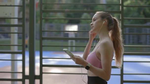 Spor Sahasına Yakın Yürüyen Kulaklığı Kulağına Takan Müzik Dinleyen Atlet — Stok video