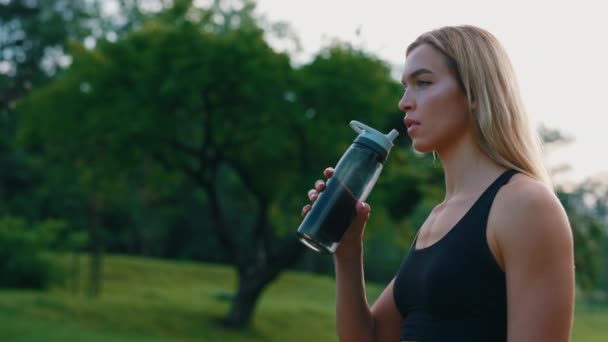 侧面看一下站在公园里的高加索女跑步者 喝着运动瓶子里的水 健康的女运动员享受户外运动训练 — 图库视频影像