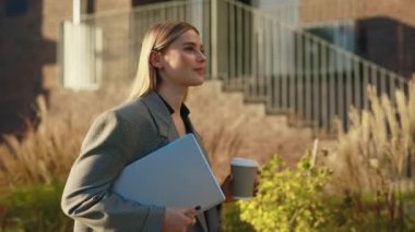 Gülümseyen genç bir kadının dizüstü bilgisayarını tutarak eve gidip kahve içişini. Bayan iş gününden sonra dışarı çıkıyor. İnsanlar ve teknoloji kavramı