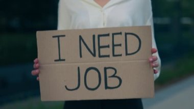 Kafkasyalı iş kadınının elleri, elinde işsiz bir iş mesajına ihtiyaç duyan karton bir poster tutuyor. İşsiz kadın yönetici. İflas, enflasyon, işsizlik. Küresel ekonomik kriz