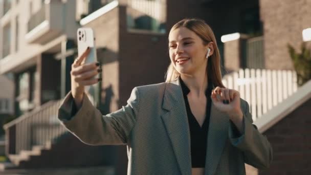 迷人的年轻高加索女人穿着正装 摆出一副智能手机相机的姿势 自拍自拍 很时髦的女人在家附近用手机拍照 — 图库视频影像