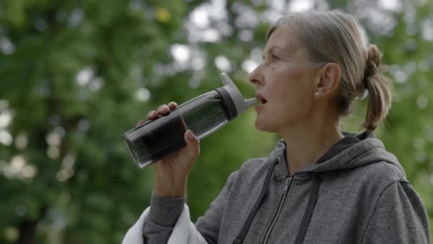 Mujer Madura Bebiendo Agua Botella Deporte Mientras Camina Mujer Anciana — Vídeos de Stock