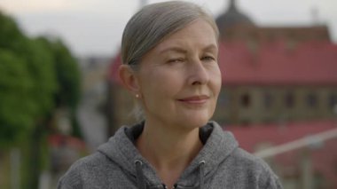 Eğitimden önce dışarıda kameraya bakan gülümseyen yaşlı kadının portresi. Spor ve sağlıklı yaşam tarzı kavramı. Genççe yaşlanmak