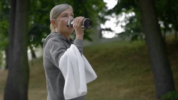 Mujer Madura Bebiendo Agua Botella Deporte Mientras Camina Parque Después — Vídeos de Stock