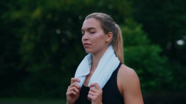 Koşmadan önce parkta duran kadın koşucunun portresi. Kameraya bakan, kulaklık takan boynunda havlu taşıyan beyaz bir sporcu. İnsanlar ve spor konsepti