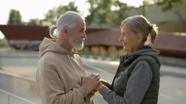 Dışarıda el ele tutuşan, kadınların ellerini öpen olgun, sevimli bir çift. Yaşlı bir aile birbirine sevgi gösteriyor, ellerini okşuyor.