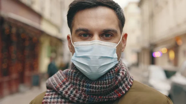 一个戴着医疗面罩的白人帅哥的近视 面带微笑地直视着相机 大家好街上的人物形象 Coronavirus流行病概念 免版税图库照片