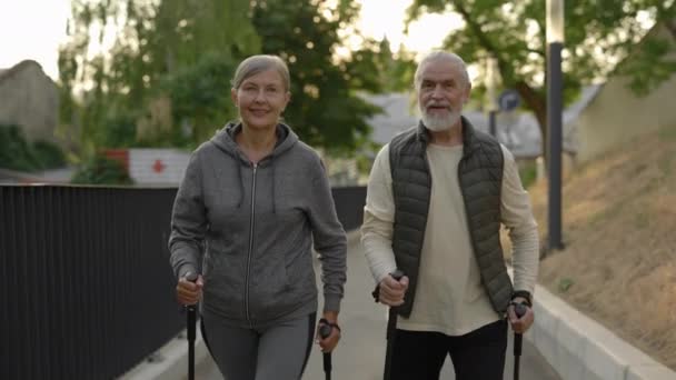 Portret Van Het Bejaarde Echtpaar Met Wandelpalen Die Door Straat — Stockvideo
