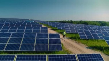 Üniformalı Erkek Teknisyen Sahada Güneş Panelleri ile Yürüyor ve Güneş Işığını Emiliyor. Alternatif Enerji Üretim İstasyonu. Elektrik, Ekoloji ve Teknoloji Konsepti