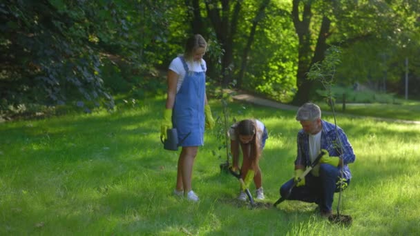 白人家庭在公园里植树 爸爸和女儿一起挖洞种花 男子正在教女童如何园艺 人与安全生态概念 — 图库视频影像