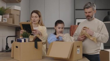 Neşeli Aile Yeni Daire 'ye yerleşir, Mutfaktaki karton kutuları açar. Kızları Açık Paketlerle Yeni Ev 'den Bir şeyler Almaya Gelen Sevimli Çift. Hareket ediyor. Gayrimenkul