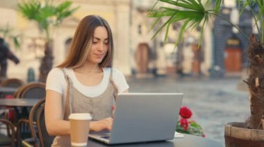 Kafkasyalı Çekici İş Kadını Serbest Çalışan Cafe Outdoor 'da dizüstü bilgisayarla çalışıyor. Bayan Çekici Ofis İşçisi Şehir Arkaplanında Oturuyor. Dışarıdaki işyerinde. Dijital Göçebe