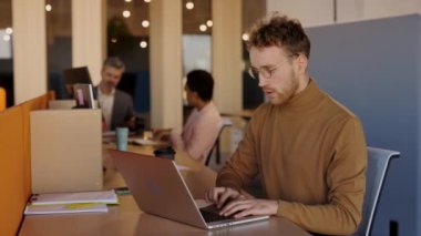 Başarılı genç iş adamı ofisteki laptopta iyi haberler alıyor. Ofis Müdürü Kazandı, Kutlamada Silahlarla Başarılı Hareketler Yapıyor. İş, Teknoloji ve İş Adamları Konseptinde Başarı