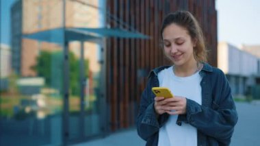 Gülümseyen Kafkasyalı Kadın Günlük Kıyafetlerle Dışarıda Yürüyor, Mesajlaşıyor ve Akıllı Telefon 'da Uygulamalar Yapıyor. Halkın Kavramı, İletişim ve Teknoloji