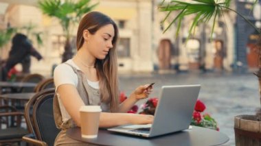 Güzel bir iş kadını bir internet sitesine kredi kartı bilgilerini yazarak bilgisayarına çevrimiçi ödeme yapıyor. Bilgisayarını ya alışveriş yapmak ya da kredi kartı kullanarak ödeme yapmak için kullanıyor.