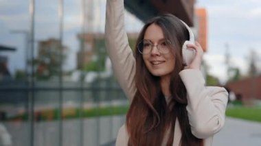 Akıllı Telefonunda Enerjik Müzik Dinlerken Dans Eden Genç Çekici Kadın. Genç ve güzel bir kadın eğleniyor. Kulaklıklı, dans eden ve gülümseyen mutlu iş kadını.