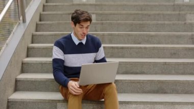 Şehir merkezindeki merdivenlerde oturan ofis işçisi dizüstü bilgisayar kullanıyor, uzaktan görüşme yapıyor, iş adamı kameraya konuşuyor. Adamın internetteki müşterilerle görüntüsü var. Halk ve Teknoloji Konsepti