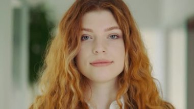 Mavi Gözlü Çekici Kızıl Ofis çalışanı içeride poz veriyor. İş kadınıyım. Güzel, güler yüzlü, kendine güvenen, güzel bir kadın. Ofisteki kamera pozuna bakıyor. Mutlu kız menajer, profesyonel.