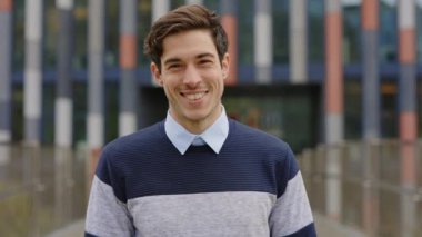 Gülümseyen genç beyaz adam. Binaların Arkaplanına Karşı Duran Yakışıklı Bir İş Adamı, Kameraya Bakıyor. Bahar Konsepti. Ön planda. Öğrenci