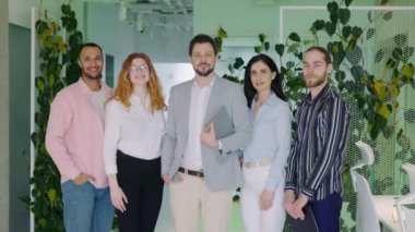 Bir grup çekici, pozitif, kendinden emin, motive olmuş erkek ve kadın resmi ofis çalışanları, yeni iş adamları, kameraya bakıyorlar. İş Adamları Portresi