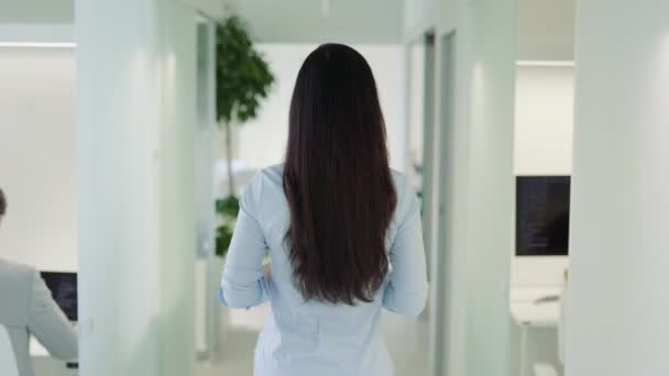 オフィスを歩く長い黒髪の若いビジネスマンのバックビュー ビジネスセンターの廊下で美しいビジネス女性 — ストック動画