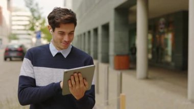 Şehirdeki Kafkasyalı Genç İşadamı Tablet Tarama Online kullanıyor. Sokak Mesajları, Kaydırma Uygulamaları 'nda çalışan gülümseyen adam. Teknoloji ve İş Konsepti