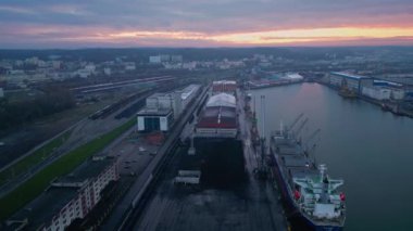 Kargo konteynır nakliye gemisi ve Crane Gdynia Sea Port Industrial District, Silhouette Sunset 'te. Lojistik Endüstri, Taşımacılık Şirketi Konsepti. Drone Hava Görüntüleme Paneli