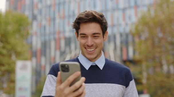 ハッピー ハンサム ワーカー マネージャー 外のモダン スマートフォンで作業 ユーザー オンライン メッセージを読む オフィスへの彼の方法で携帯電話を使用して若い起業家 — ストック動画