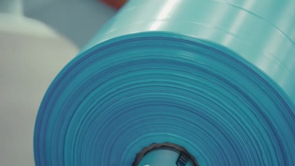 ガベージ袋の生産ライン ゴミ袋のロール クローズアップ ファクトリー 工場リールを介して転がる青いポリエチレンパッケージ — ストック動画