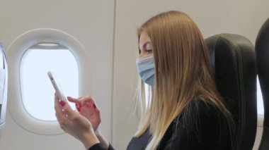 Salgın sırasında Özel Uçakta Seyahat Ederken Maskeli Kadın Cep Telefonu Kullanıyor. Zengin Kız Cep Telefonu Kullanıyor ve Birinci Sınıf Havayollarında Şatafatlı Yolculuğun keyfini çıkarıyor.