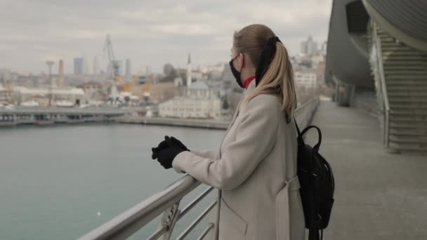戴护目镜的女士站在外面的桥上 望着远方 检疫后旅行 科维德期间的游客 健康及安全寿命概念 — 图库视频影像