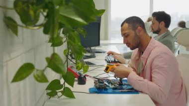 Çoklu Etnik Erkek Yakışıklı Usta Mühendis Çipin sıcaklığını Pyrometer ile ölçüyor. Guy Kaynak Araçları ve Ana Kart Sıcaklığını Ölçüyor
