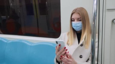 Güvenli Maskeli Turist Kız metro koltuğunda oturuyordu. Metro 'daki kadın, salgın sırasında, toplu taşımada kendini koruma, Metro' da bir cihaz üzerinde çalışıyor. Ulaşım, Teknoloji ve Kapsamlı Konsept
