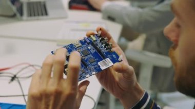 Beyaz tenli yakışıklı mühendis ana kartı kontrol ediyormuş. Erkek Tutma Mikro Devresi. Elektronik Onarım ve Test. Ofis İşi