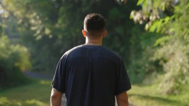 Çok ırklı Erkek Turist Arkadan Görüldü, Parkta Gezinti Yapıldı, Ayağın Altındaki Bölgeyi Keşfediyor. Yolda yürüyen genç bir adam var. Turizm ve Seyahat Konsepti