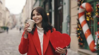 Süslü caddede yürüyen, kahve ya da çay içen, kalp şeklinde sevgililer günü hediyesi taşıyan beyaz bir kadın. Şehir merkezinde kırmızı hediyeyle yürüyen esmer kadın.