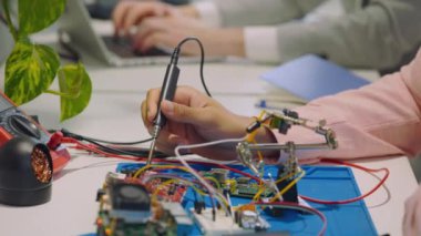 Bir teknoloji şirketinde çipleri bir devre kartına lehimleyen bir teknisyenin yakın çekimi. Gömülü programcı. Teknik onarım ve araştırma kavramı
