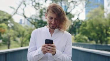 Yakışıklı Sakallı ve Hedef odaklı İşadamı Halka Açık Park 'ta yürürken Smartphone Kullanarak Geri Gelen Müşterilere Mesaj Yazıyor. İş İnsanları ve Teknoloji Konsepti