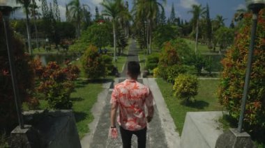 Başarılı bir genç adamın gölün üzerindeki köprüde parka yürürken ki görüntüsü. Excursion 'da çok ırklı erkek gezgin. Turizm ve Seyahat Konsepti