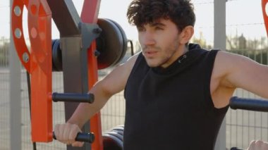 Çekici Sakallı Spor Adamı Yapan Basın 'ın Kapanışı. Egzersiz makinelerini kullanarak Arkaya ve Kollara Antrenman yaptıran genç adam. Halk ve Spor Konsepti
